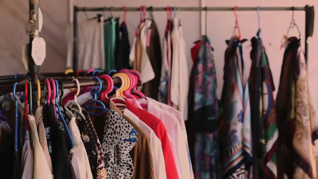 Women picks up blouse from clothing rack